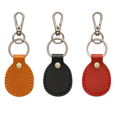 Three leather keychains in orange, black, and red on a white background